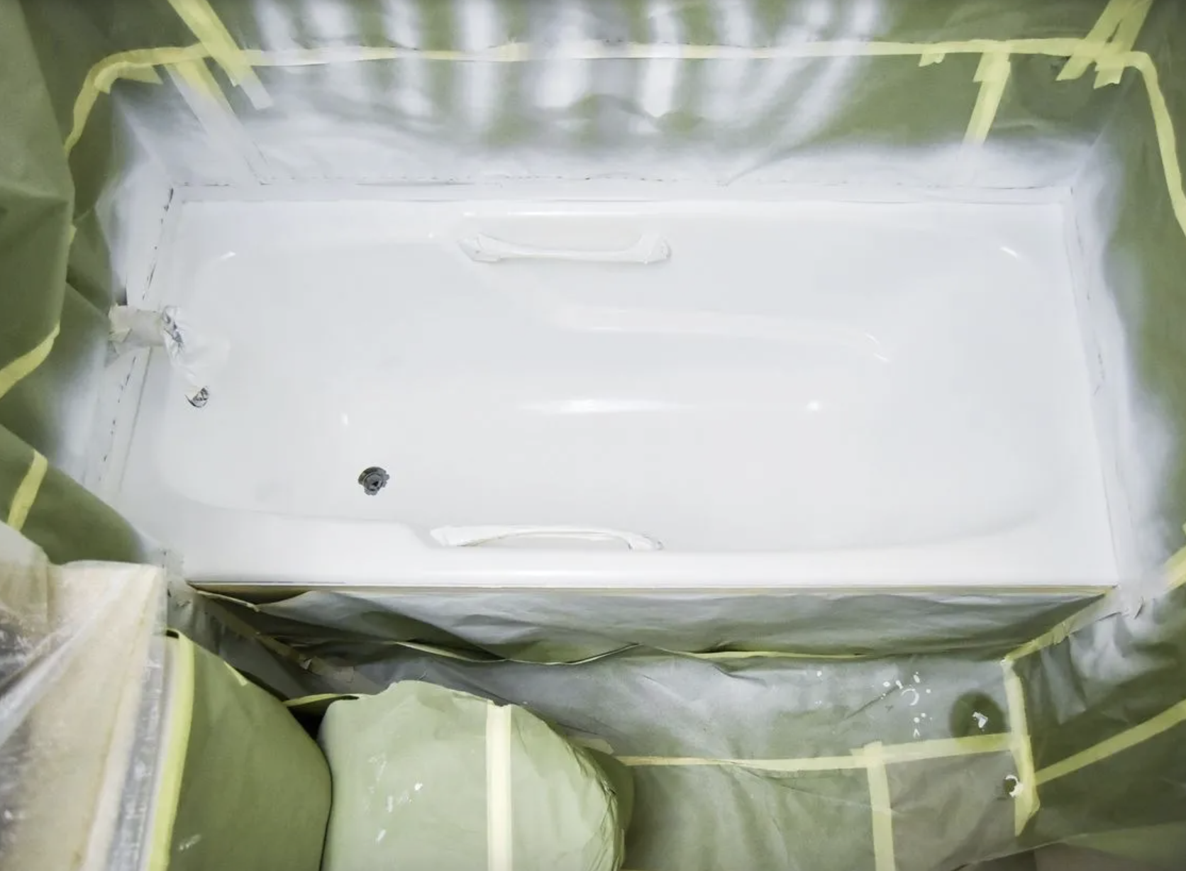 Bathtub refinishing job in progress with protective masking